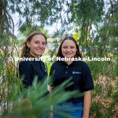 Husker undergraduates Abigail Schroeder (left) and Emma Kurtz are among coauthors of a new study indicating that Norfolk could achieve significant cost savings and reduced landfill use by integrating its solid waste and energy systems. The students’ work continues the university’s tradition of engagement and research on environmental issues in Norfolk. The two are photographed in the trees by Hardin Hall. October 12, 2023. Photo by Kristen Labadie / University Communication.